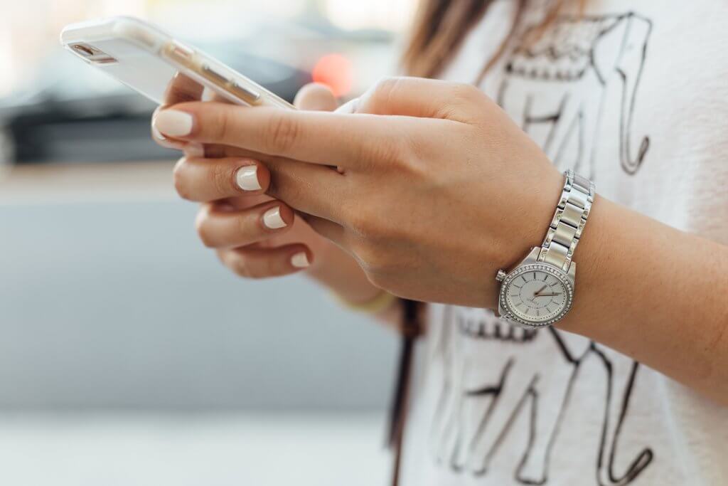 Woman wearing a watch texting on iphone
